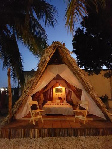 a tent with a bed and two chairs in it at El Búho Glamping Bacalar in Bacalar