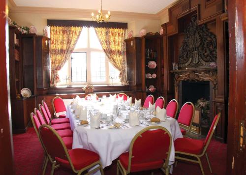 a dining room with a table and red chairs at Weston Hall Hotel Sure Hotel Collection by Best Western in Bulkington