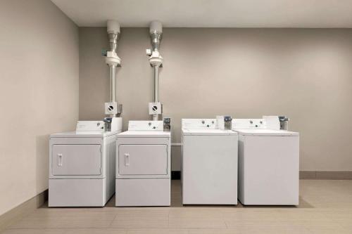 a row of white washers and dryers in a room at La Quinta Brunswick/Golden Isles in Brunswick
