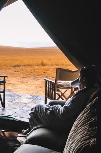 a woman sitting in a tent looking out at a field at Cradlestone Camp in Krugersdorp