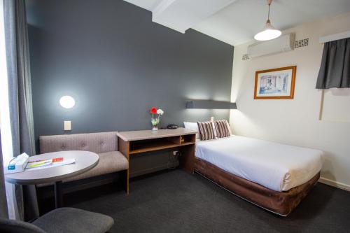 ein kleines Hotelzimmer mit einem Bett und einem Schreibtisch in der Unterkunft The Midcity Motor Lodge in Orange