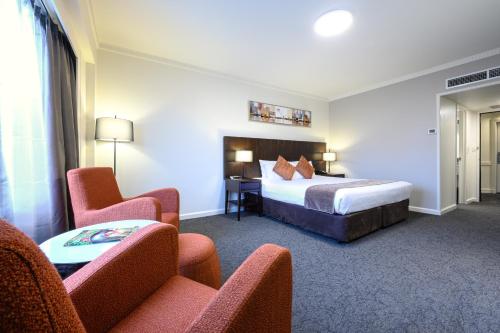 a hotel room with a bed and chairs at Hotel Grand Chancellor Adelaide in Adelaide