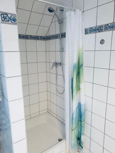 a shower in a white tiled bathroom at Kehrwieder in Warnemünde