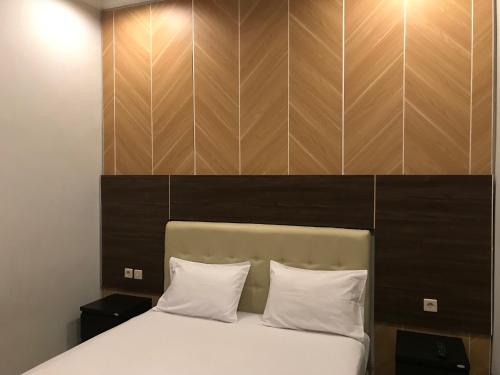 日惹的住宿－諾拉度假屋，一张带两个白色枕头和木制床头板的床