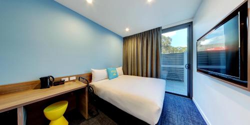 a room with a bed and a desk and a window at ibis budget Sydney Airport in Sydney