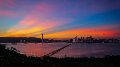 a sunset over a large body of water with a city at YOHO Hollywood Roosevelt Hotel in Macau
