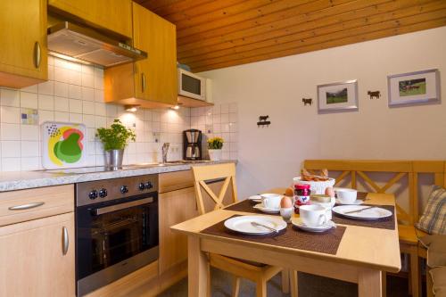 eine Küche mit einem Holztisch mit Geschirr darauf in der Unterkunft Ferienwohnungen Alpentraum - Landhaus Schmetterling in Oberstdorf