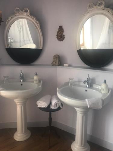 a bathroom with two sinks and two mirrors at Château de Varennes in Varennes-lès-Mâcon