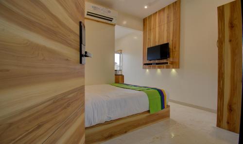 a bedroom with a bed and a tv on a wall at Hotel Amisha International in Surat