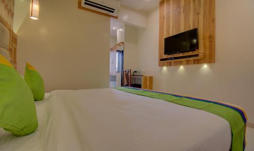 a bedroom with a large white bed with a flat screen tv at Hotel Amisha International in Surat