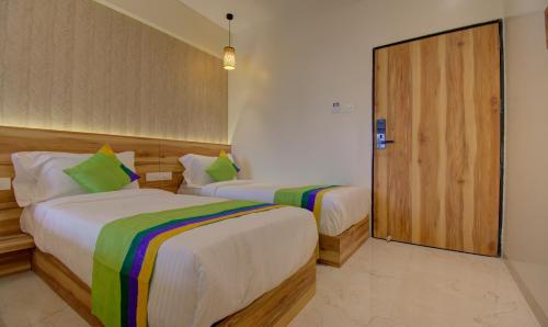 a bedroom with two beds and a wooden door at Hotel Amisha International in Surat