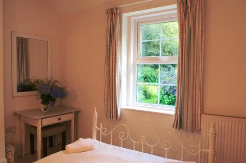 1 dormitorio con cama y ventana en Little Dunbar Cottage, en Kirkbean