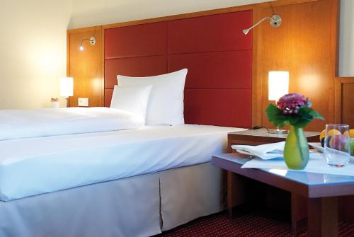 a hotel room with a bed and a table with a vase of flowers at Morada Hotel Heidesee Gifhorn in Gifhorn