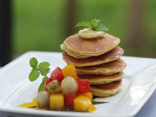 a stack of pancakes on a white plate with fruit at Tanei Angkor Resort and Spa in Siem Reap