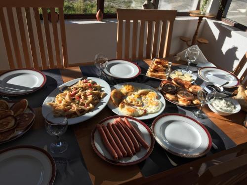 a table with plates of food and wine glasses at Beko’s garden Inn in Mestia