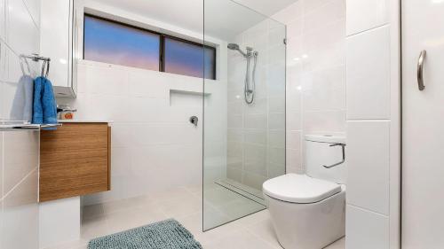 a white bathroom with a shower and a toilet at Beach Point - East Ballina in East Ballina