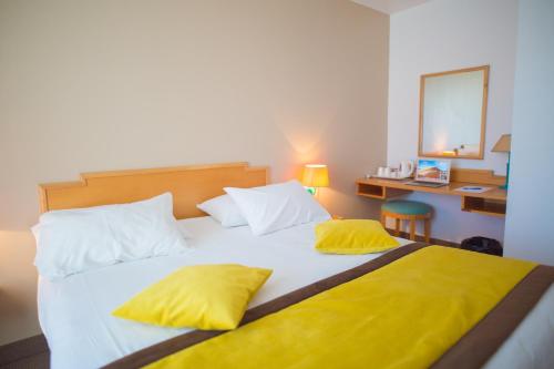 a bedroom with a large bed with yellow pillows at Golf Hotel de Mont Griffon in Luzarches