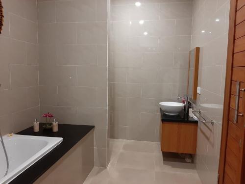 ein Badezimmer mit Badewanne und Waschbecken in der Unterkunft The Satya Villa in Ubud