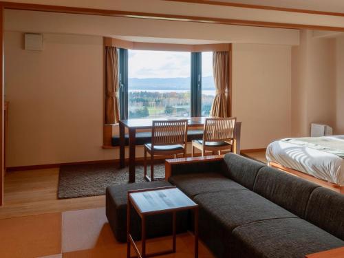 a hotel room with a couch and a bed and a table at Hokuten no Oka Abashiriko Tsuruga Resort in Abashiri