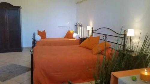 1 dormitorio con 1 cama con colcha de color naranja en B&B Antonella, en Perito