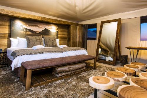 a bedroom with a bed and a mirror and tables at Dead Valley Lodge in Sesriem
