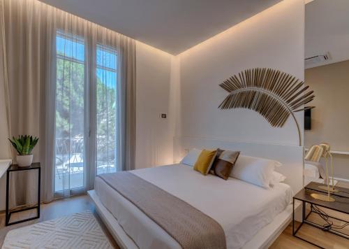 a bedroom with a white bed and a large window at Le Palmette Suites in Cagliari