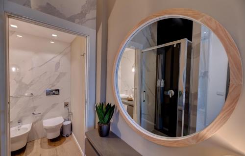 a bathroom with a round mirror and a sink at Le Palmette Suites in Cagliari