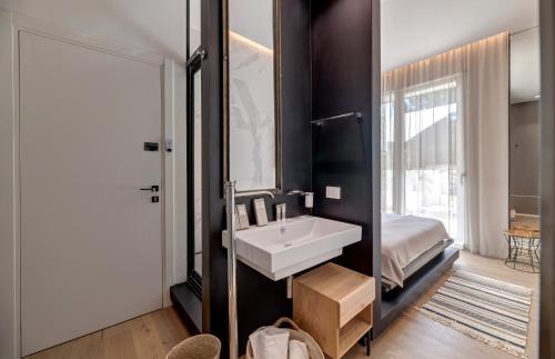 a bathroom with a sink and a bed and a mirror at Le Palmette Suites in Cagliari