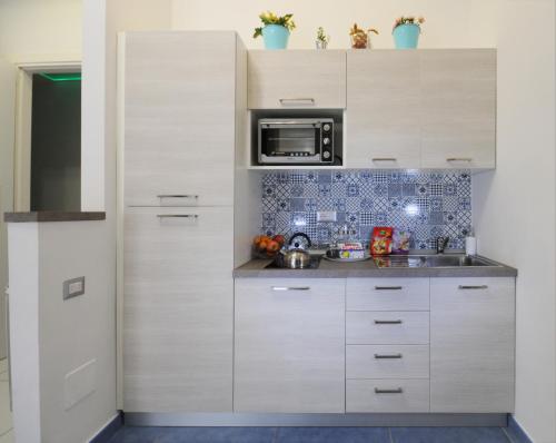 a kitchen with white cabinets and a microwave at Casa Sassolini in Naples