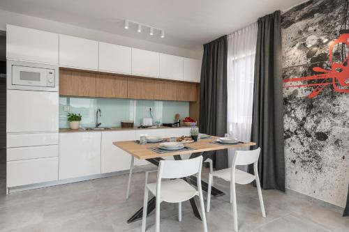 a kitchen with a wooden table and white cabinets at Residence Alpha Apartments in Cavtat