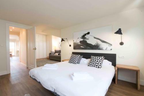 una camera da letto con un grande letto bianco con cuscini di The Rentals Collection | Costa a San Sebastián