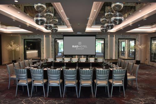 a conference room with a long table and chairs and a screen at Dalmeny Park House Hotel in Barrhead
