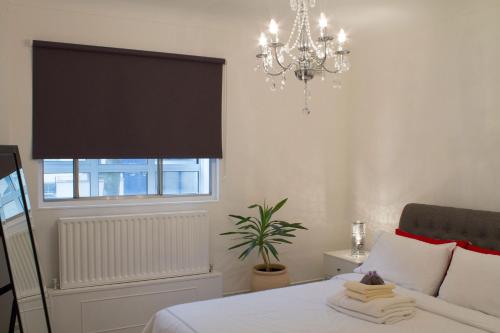 1 dormitorio con 1 cama con lámpara de araña y ventana en Baker Street Style, en Londres