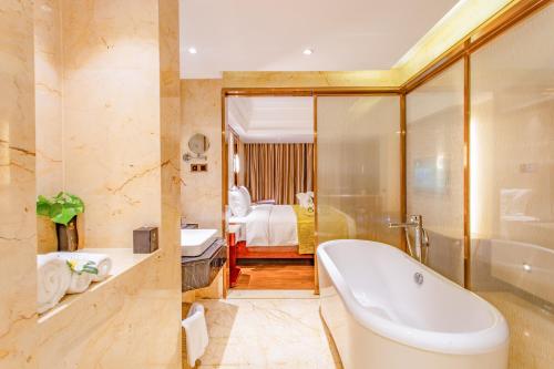a bathroom with a tub and a bedroom at YueXin Tomorrow Hotel Sanya in Sanya