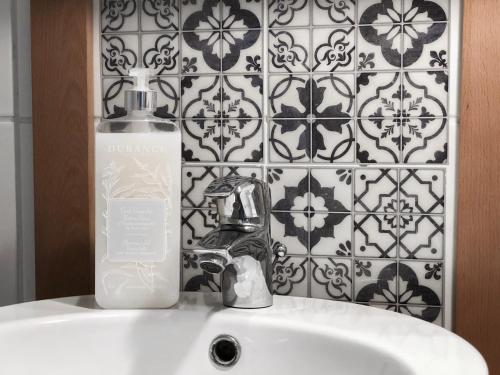 a bathroom sink with a bottle of soap on it at HAPPY MAMA COLMAR with PARKING in Colmar