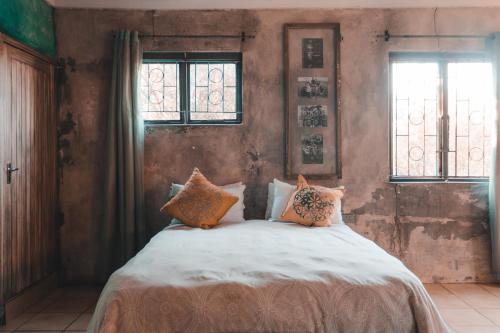 a bedroom with a bed with pillows and two windows at The Prawn Hatchery Pty Ltd on Amatikulu in Dokodweni
