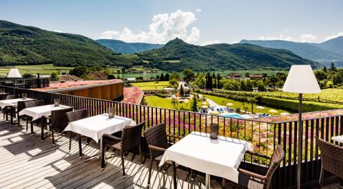 a balcony with tables and chairs and a view of mountains at Hotel Thalhof am See in Caldaro