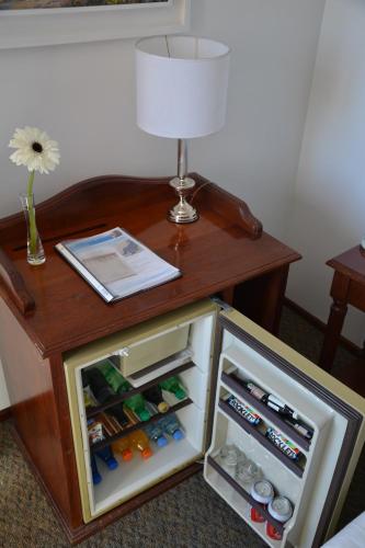 a small table with a lamp and an open refrigerator at Hotel de la Cañada in Cordoba