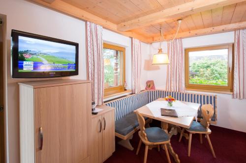 a living room with a television and a table and chairs at Landhaus Greil in Reith im Alpbachtal