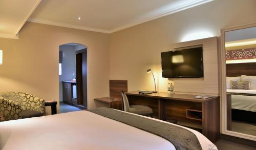 a hotel room with a bed and a desk and a television at Birchwood Hotel and OR Tambo Conference Centre in Boksburg
