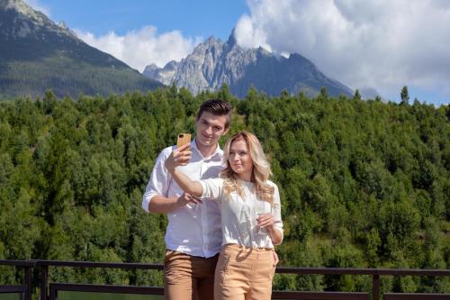 a man and a woman taking a picture with a cell phone at Grand Hotel BELLEVUE in Smokovce