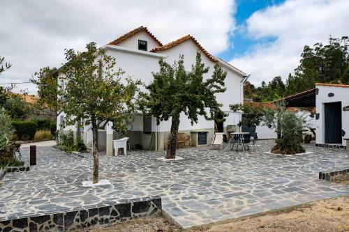 a house with a courtyard with trees in front of it at Casa do Ferreiro II in Góis