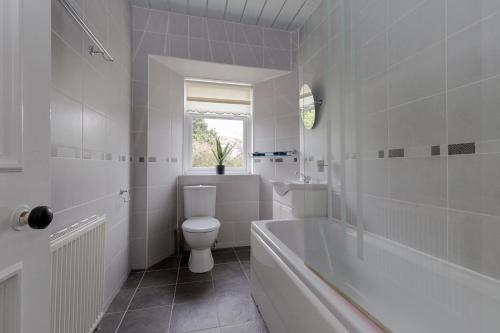 a bathroom with a tub and a toilet and a sink at The Midsands Apartment in Ayr