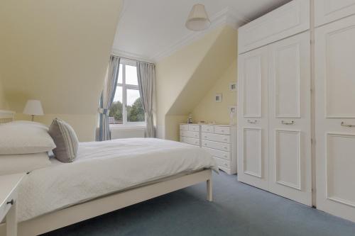 a white bedroom with a bed and a dresser at The Midsands Apartment in Ayr