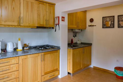 a kitchen with wooden cabinets and a stove top oven at Casa do Ferreiro II in Góis