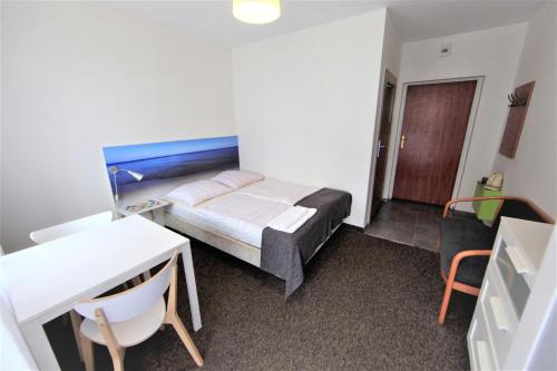 a small bedroom with a bed and a desk and a table at Willa Park Międzyzdroje in Międzyzdroje