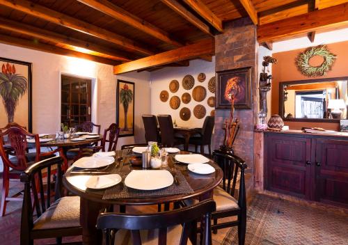 a dining room with tables and chairs and a kitchen at Ama Zulu Guesthouse & Safaris in Hluhluwe