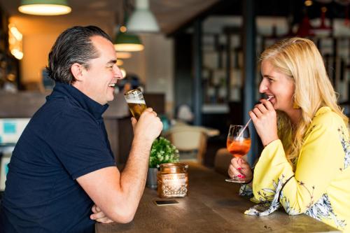 un homme et une femme assis à une table avec des boissons dans l'établissement TopParken – Résidence Valkenburg, à Fauquemont