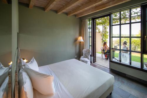 a bedroom with a bed and a woman sitting in a chair at Le Ali Del Frassino in Peschiera del Garda