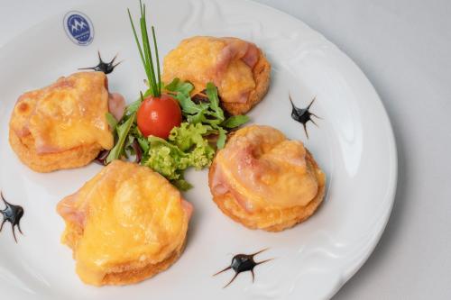 a white plate with four food items on it at Grand Hotel BELLEVUE in Smokovce